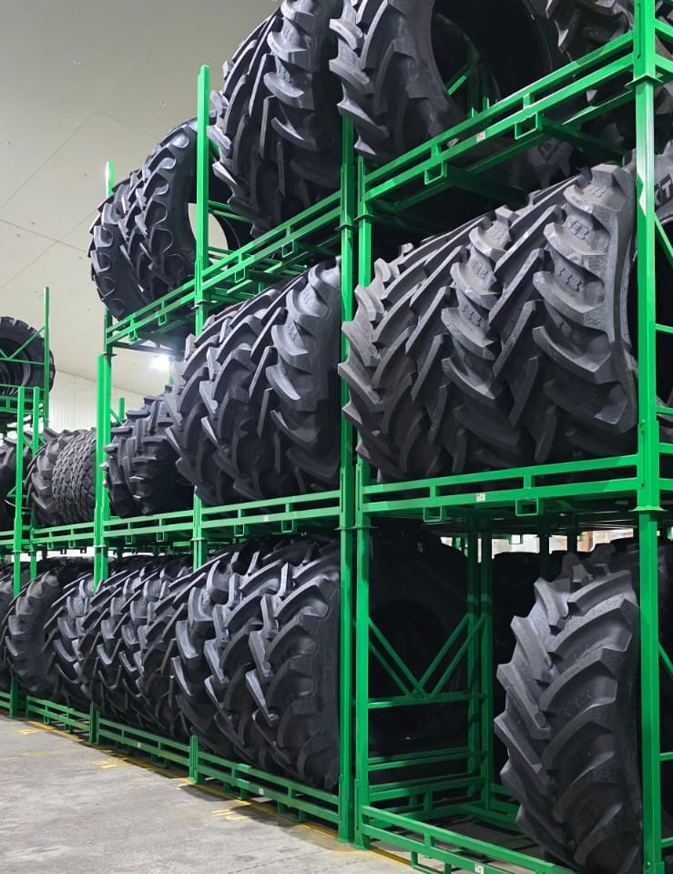 Green Stacked tractor and OTR tyre stillages stacked in a warehouse