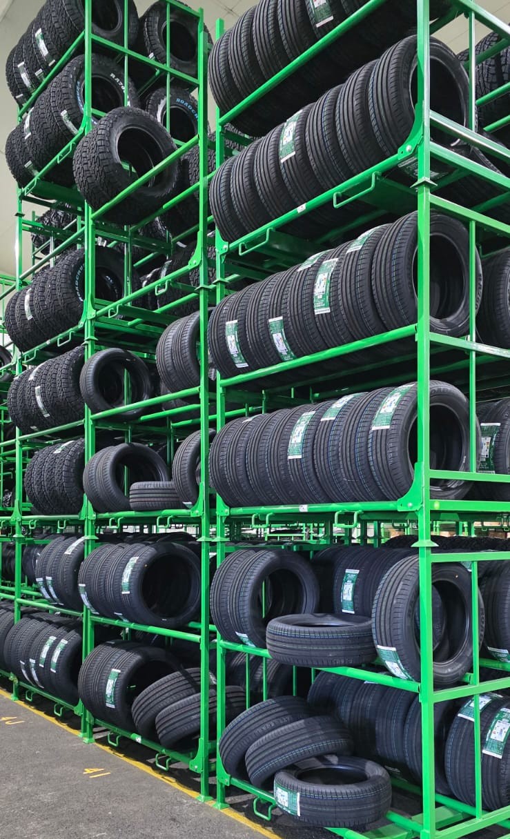 Green Stacked car tyre stillages stacked high in a warehouse, loaded with car tyres